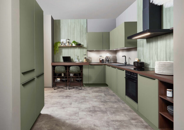 Grüne Einbauküche mit matten Fronten, Holzdetails und integriertem Arbeitsplatz, die modernes Design mit praktischer Nutzung kombiniert