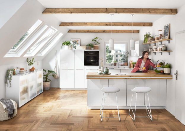 Helle Küche mit Kochinsel, Holzarbeitsplatte und Sitzbereich, die offene Raumgestaltung und komfortables Kochen ermöglicht