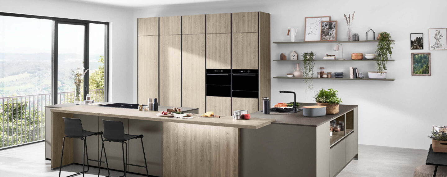 Moderne Küche mit Holzoptik, großzügiger Kochinsel und integrierten Elektrogeräten, die offenen Stauraum, Sitzplätze und funktionales Kochen im Wohnraum vereint
